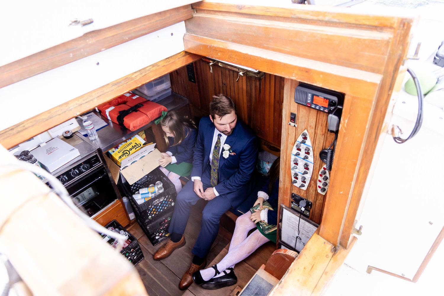 Aerial view of a groom in navy suit inside a wooden boat cabin preparing for his wedding day.