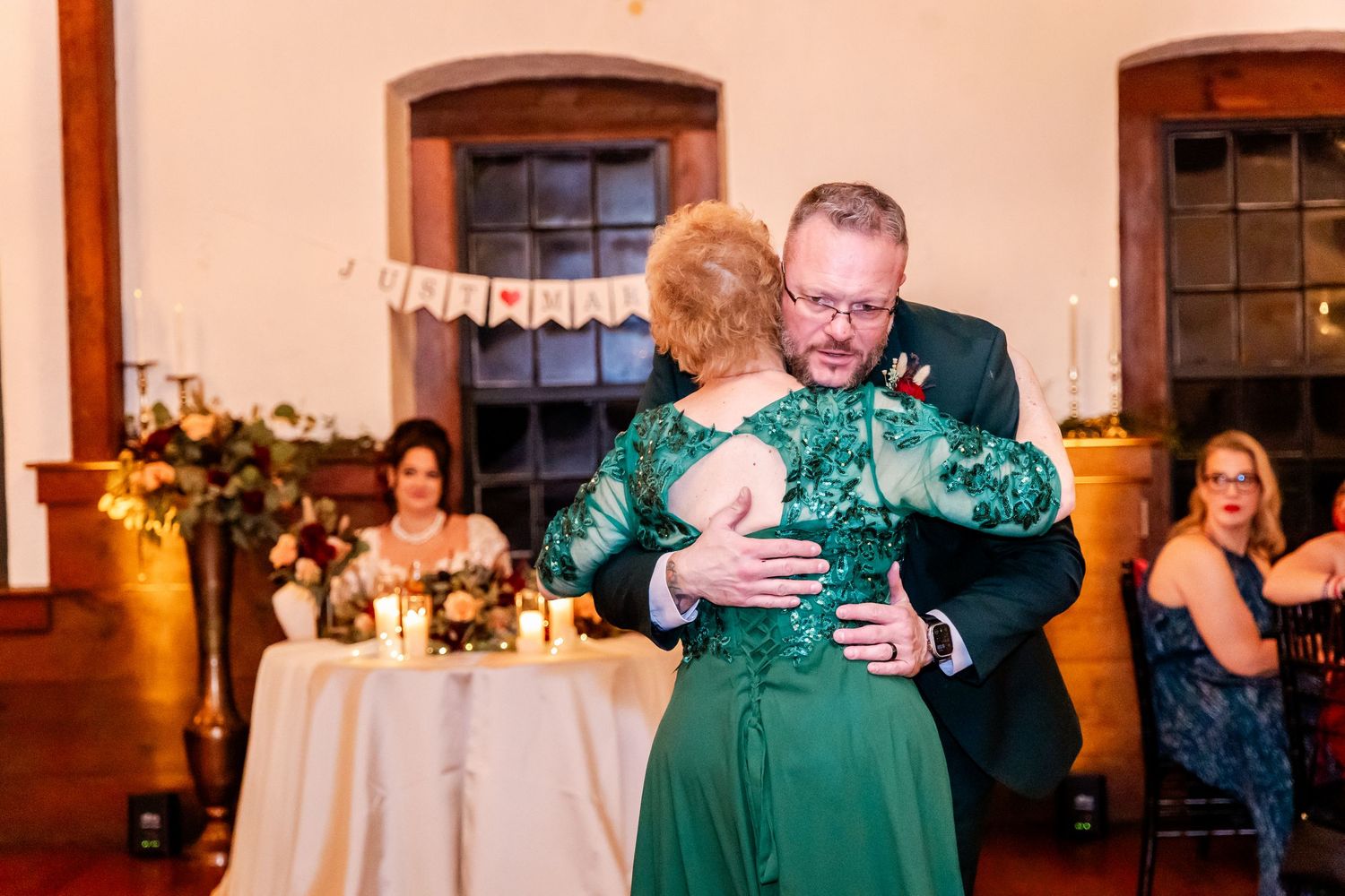 Wedding dance in an elegant venue with warm lighting and round tables.
