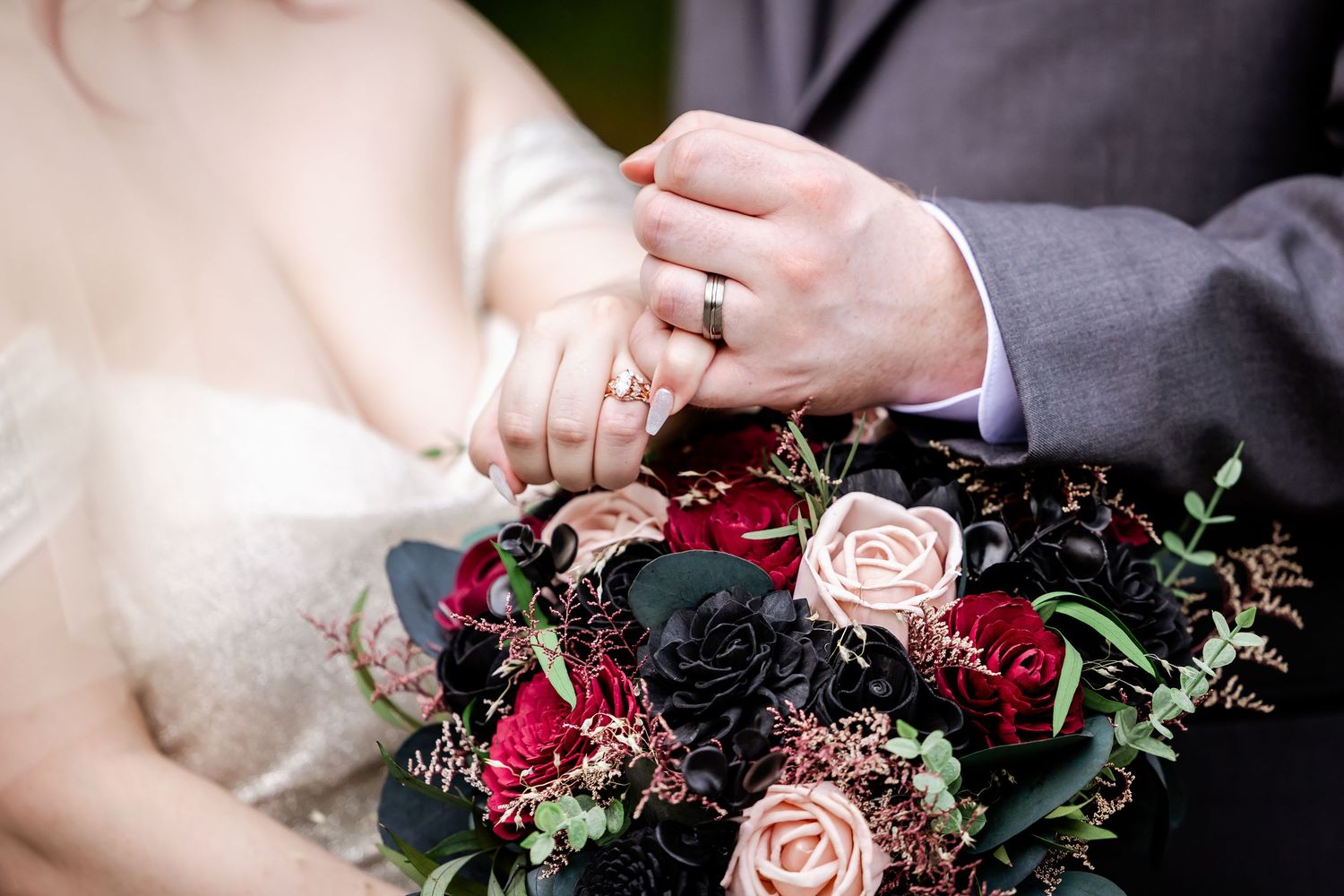 A wedding bouquet with deep burgundy and blush pink roses against a dark background creates elegant contrast.