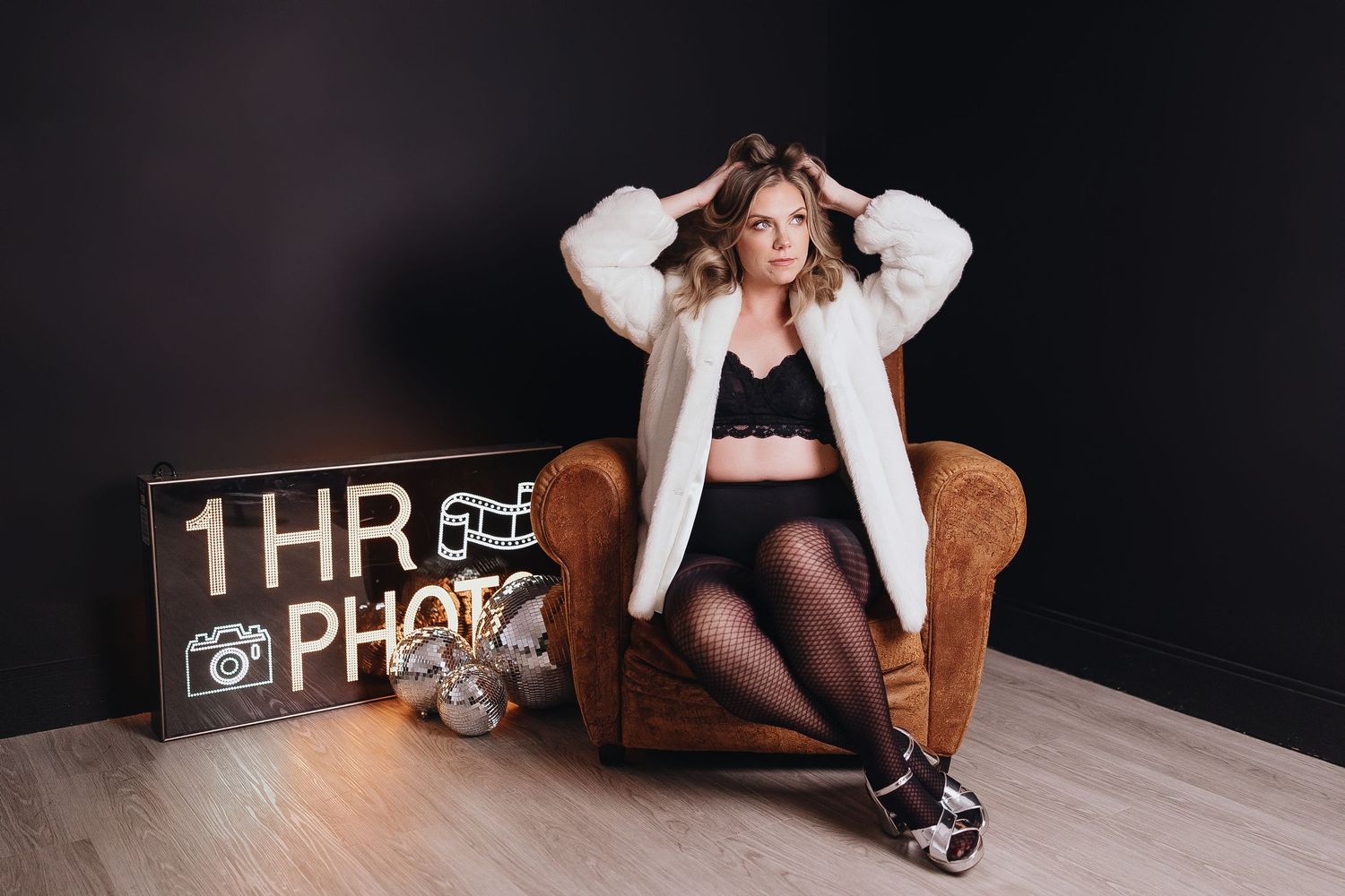 Artistic boudoir photography session featuring dark moody lighting and leather furniture.