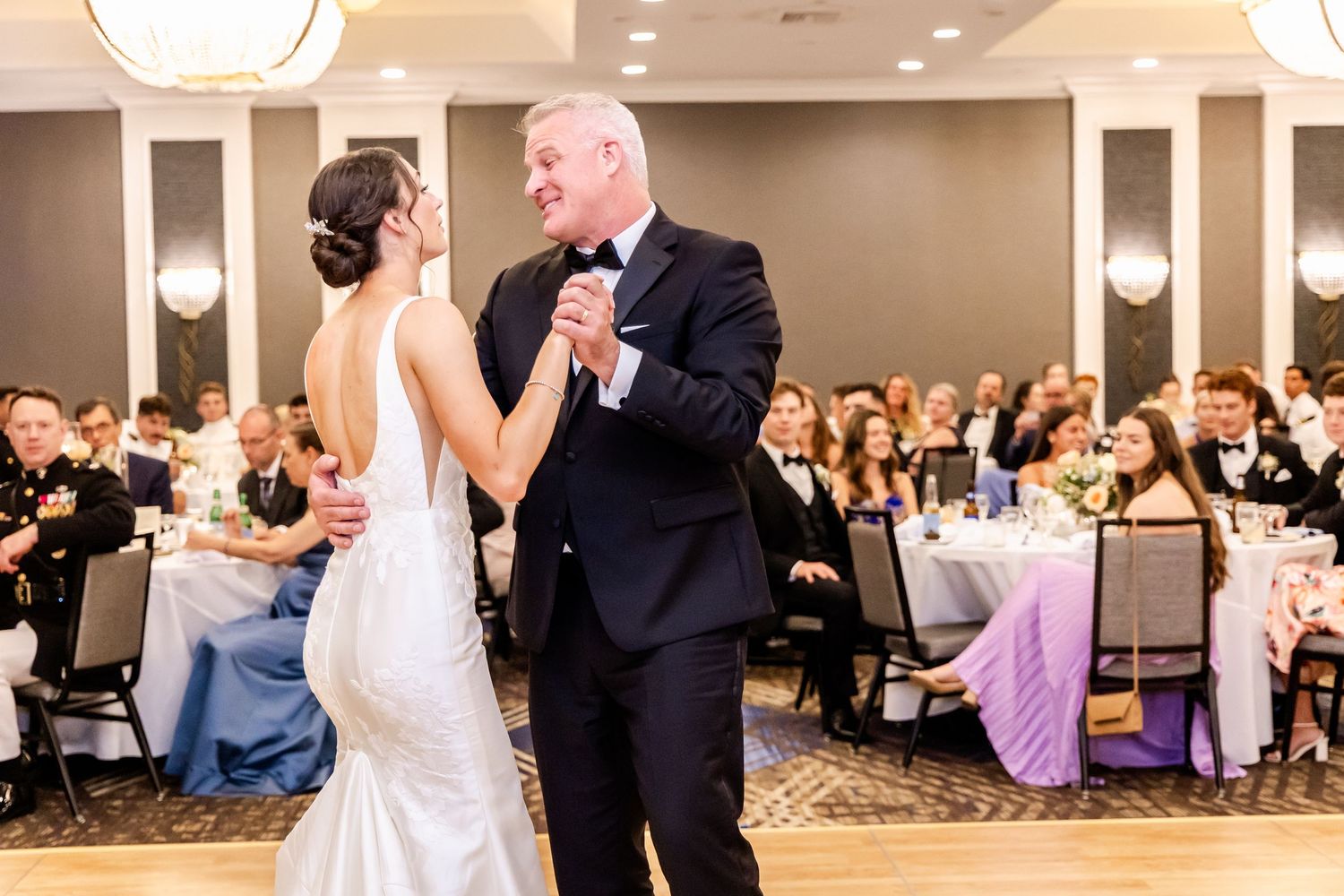 Couple shares an elegant dance moment in a beautifully lit ballroom during wedding reception.