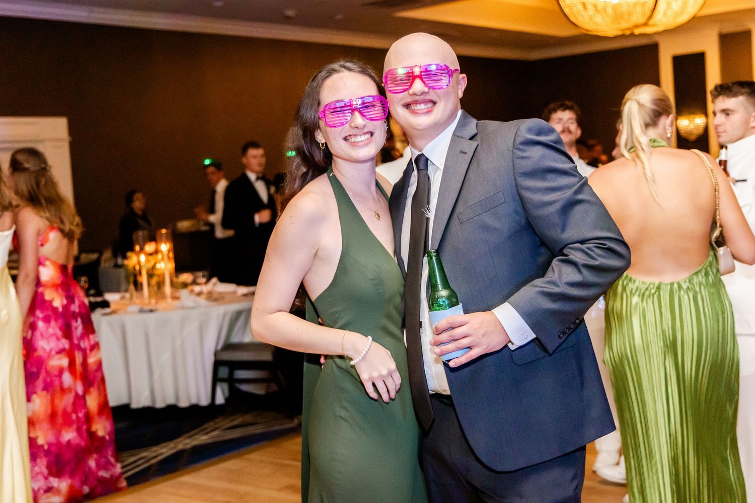 Wedding guests in colorful attire dancing and celebrating at an indoor reception venue.