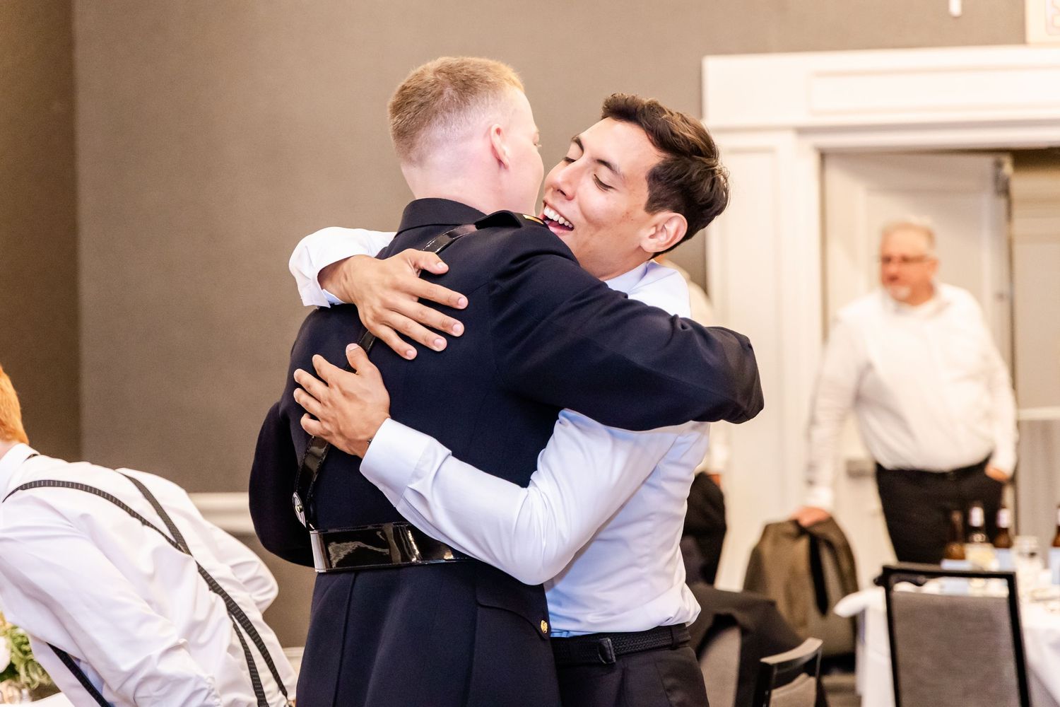 People embracing and hugging during an emotional moment at a formal event.