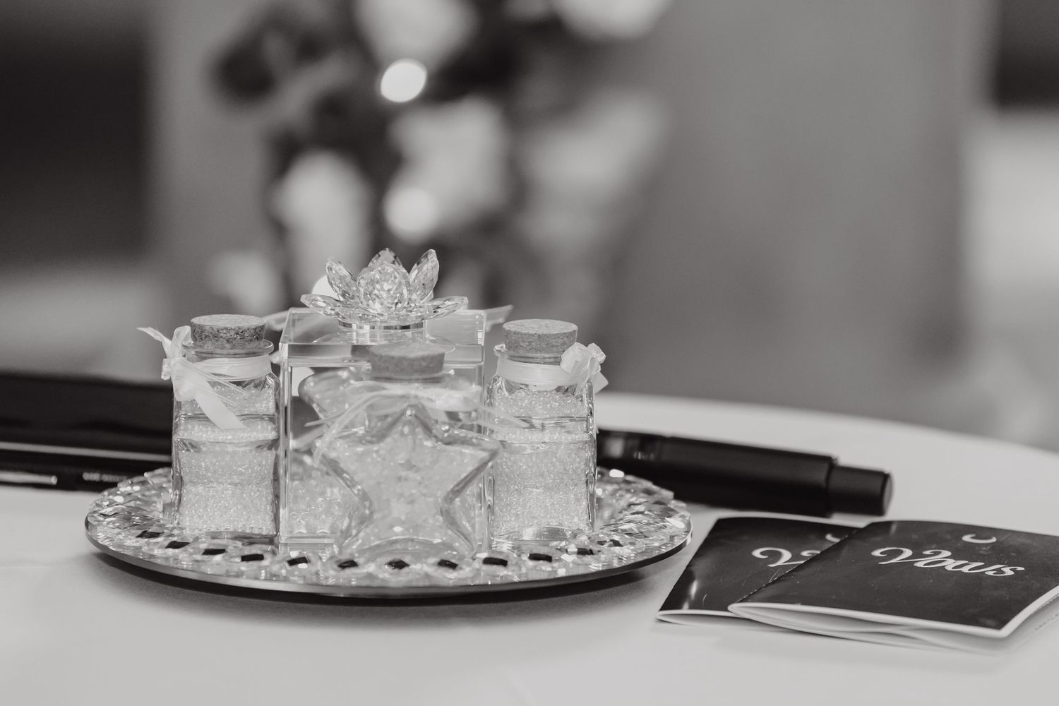 Black and white photo of decorative crystal shot glasses arranged on a silver tray at a wedding reception.