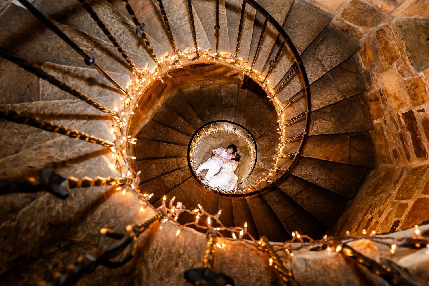 Spiral stone staircase illuminated with string lights creating a magical ambiance.