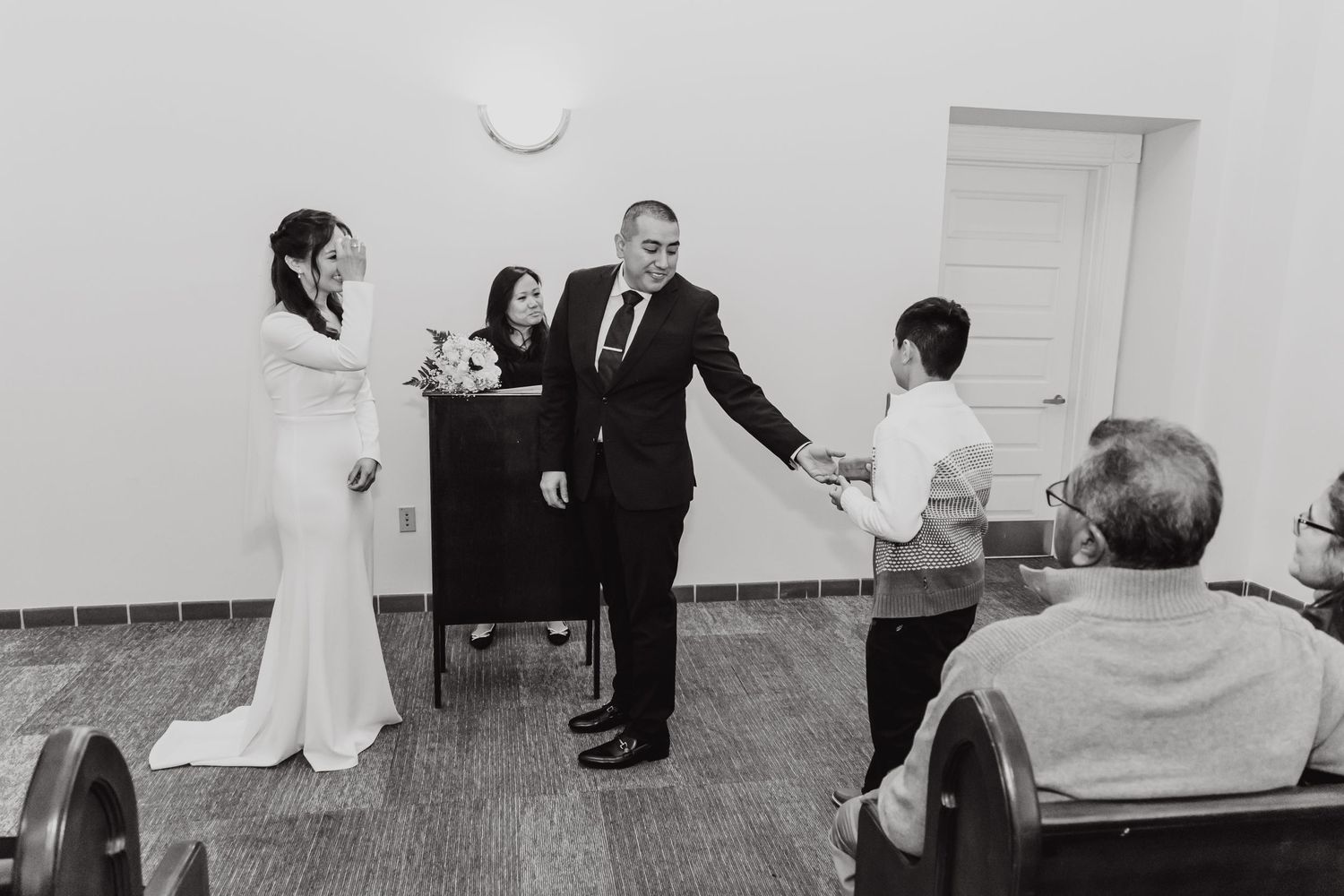 Black and white photo of a wedding ceremony in a minimalist indoor setting.