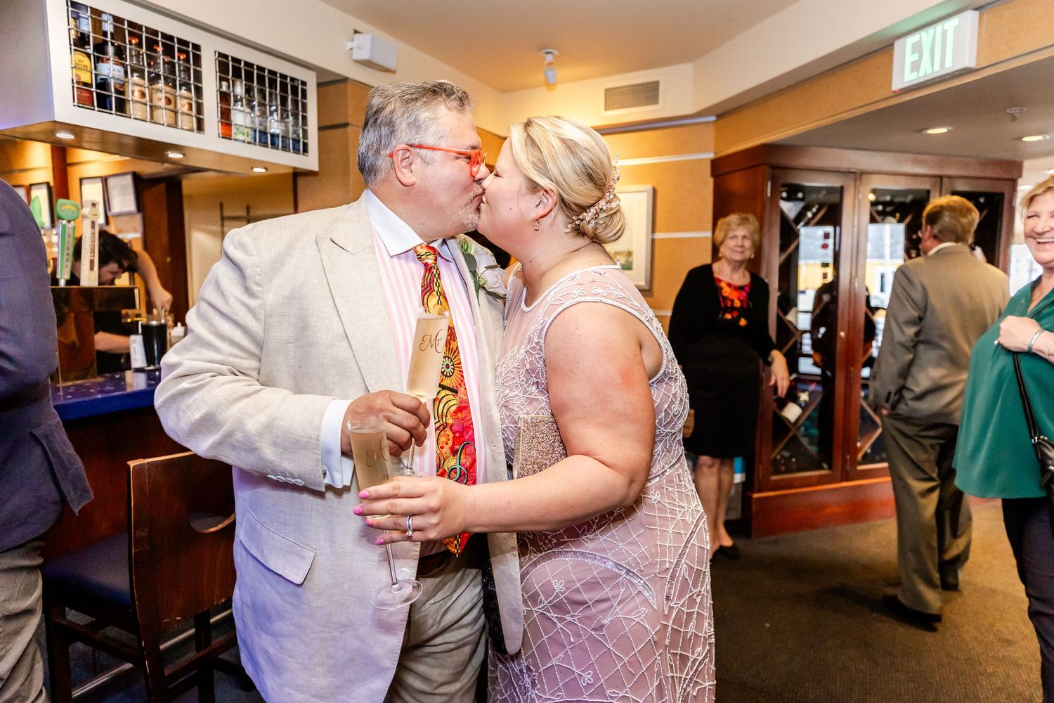 Couple sharing intimate moment at celebration event near bar area.