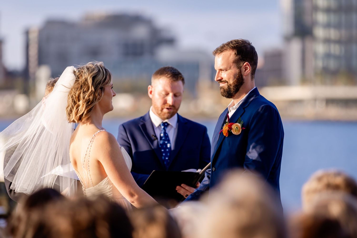 Wedding ceremony taking place on a pier with the city skyline in the background.