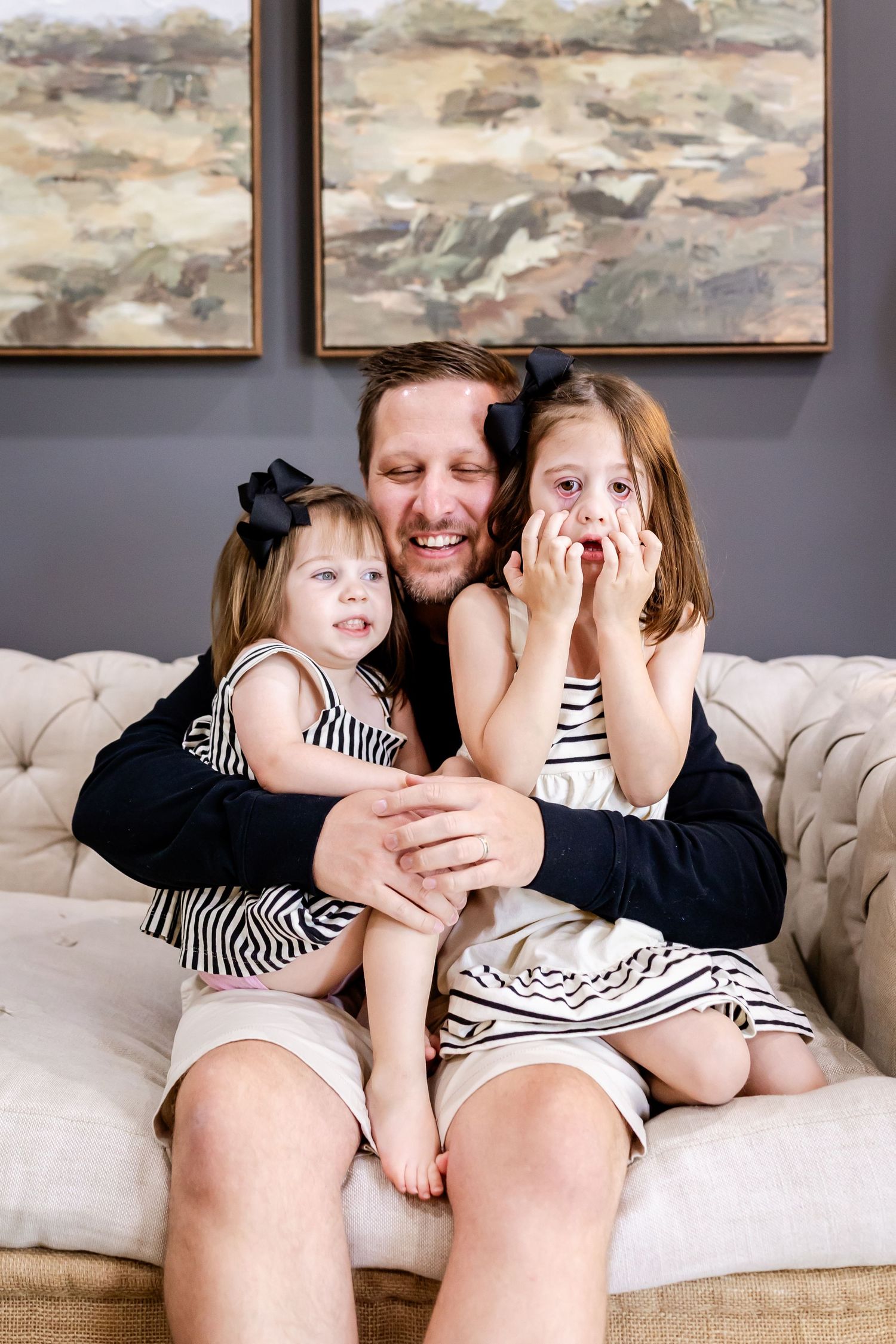 A family lounges together on a light colored couch while sharing moments of laughter and joy.