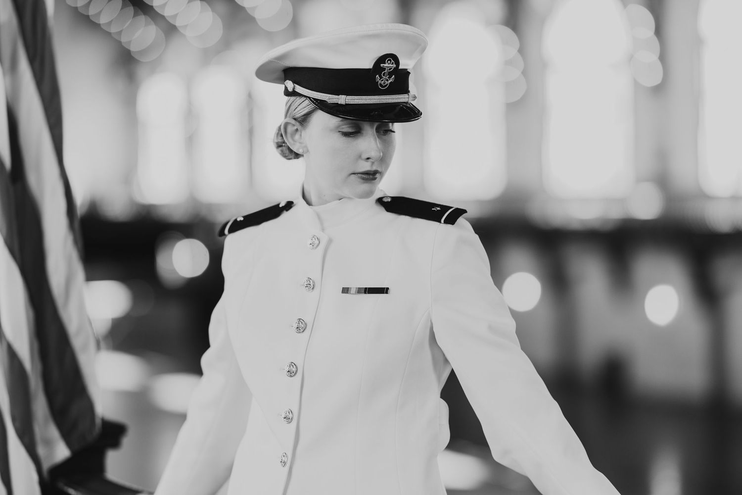 A vintage black and white photo showing a person in formal naval officer uniform with cap and white jacket.