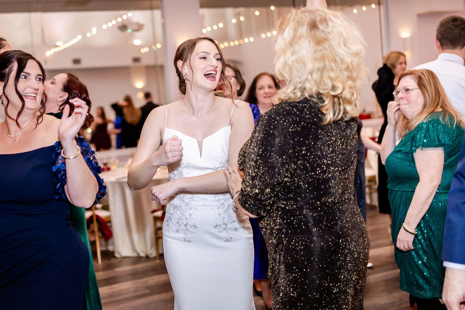 Wedding reception dance party with guests enjoying themselves in a bright indoor venue.