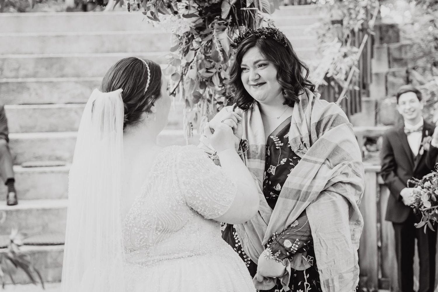 Black and white candid moment of wedding ceremony with guests on outdoor steps.