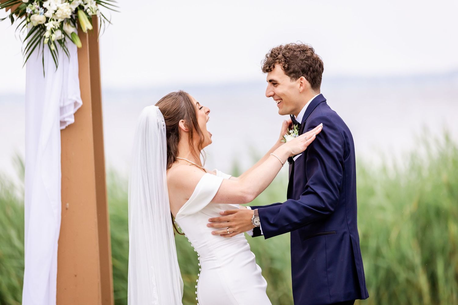 Romantic outdoor wedding ceremony moment with coastal scenery in the background.