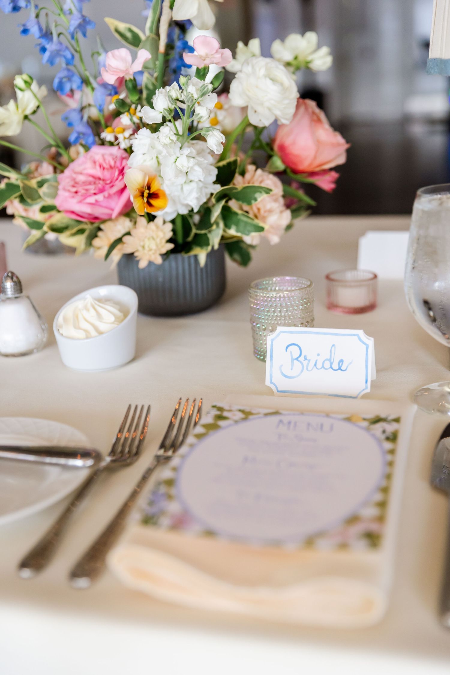 Elegant wedding table settings with delicate floral centerpieces in pink and blue with crystal accents.