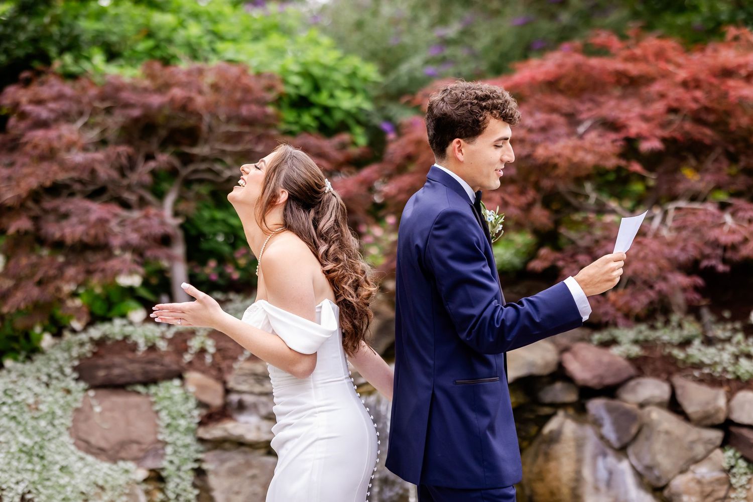 Wedding couple walking through garden with Japanese maple trees.