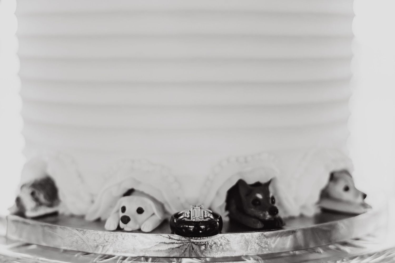 Close-up of decorative wedding cake details with small figurines along the base in black and white.