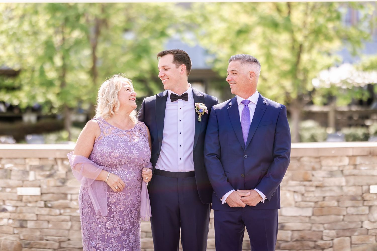 Wedding party members posing against a stone wall backdrop.