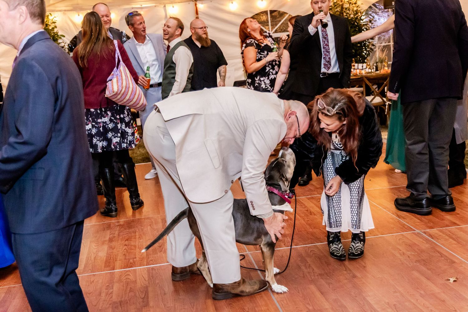 Wedding guests enjoying dance floor at indoor reception venue.