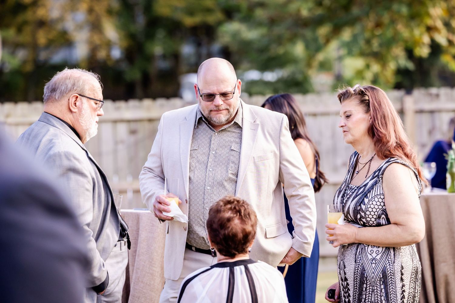Small group of guests chatting during an outdoor wedding reception.