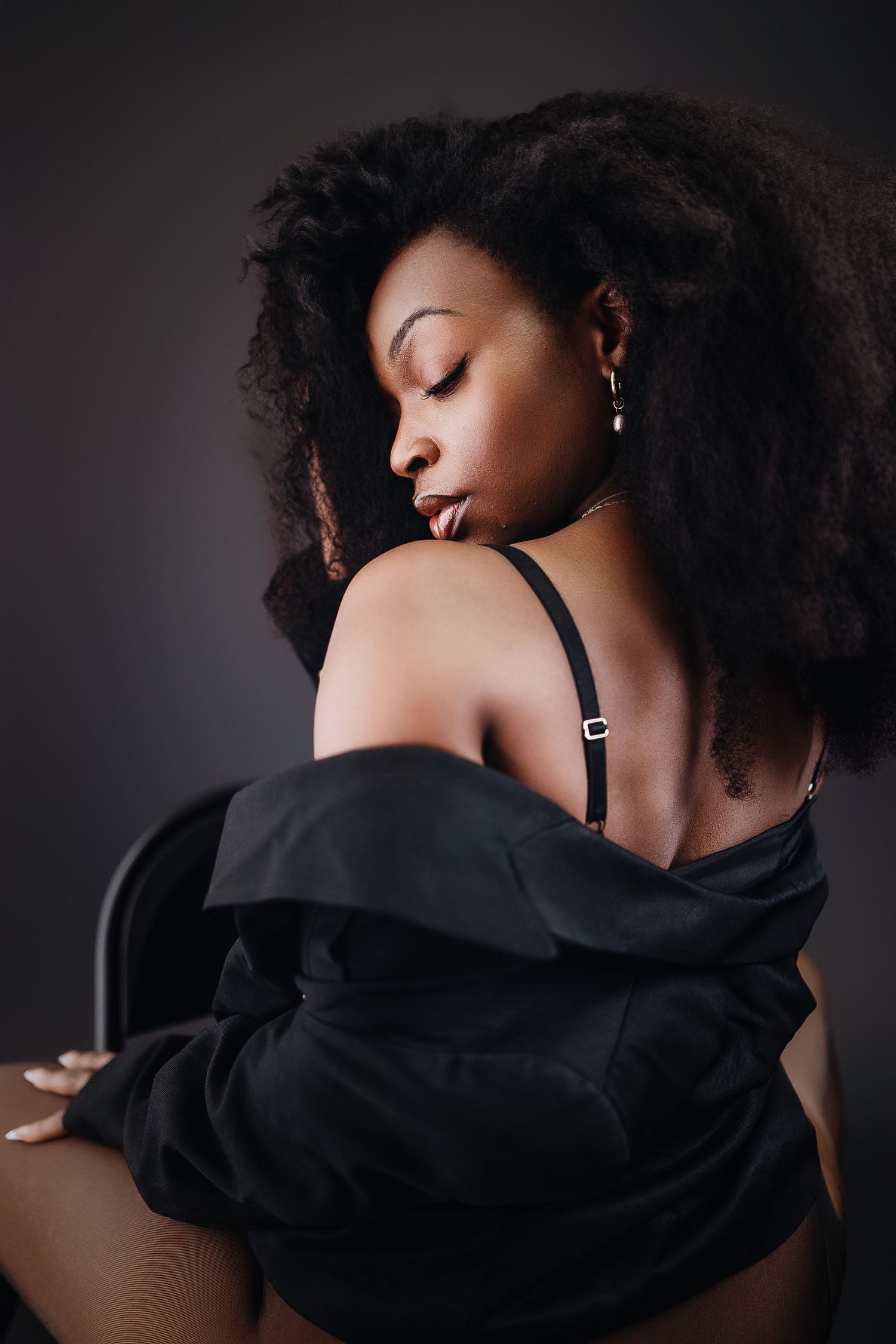 Artistic portrait series showing a person with natural curly hair wearing a black top against dark background.