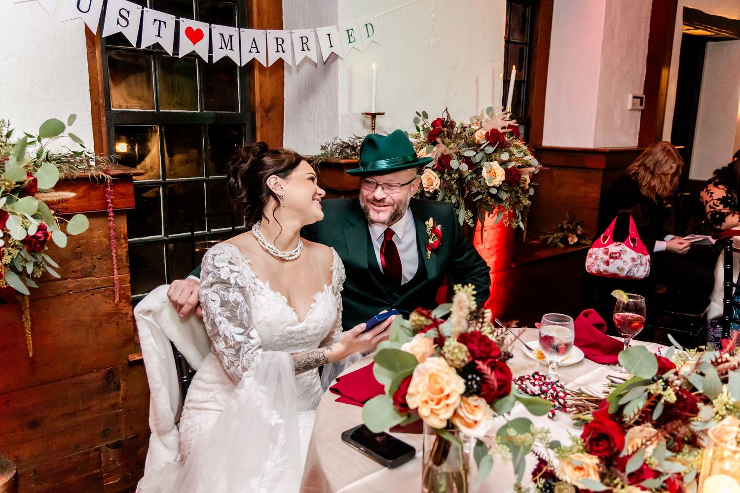 Wedding reception hall decorated with white banners and floral arrangements on dining tables.