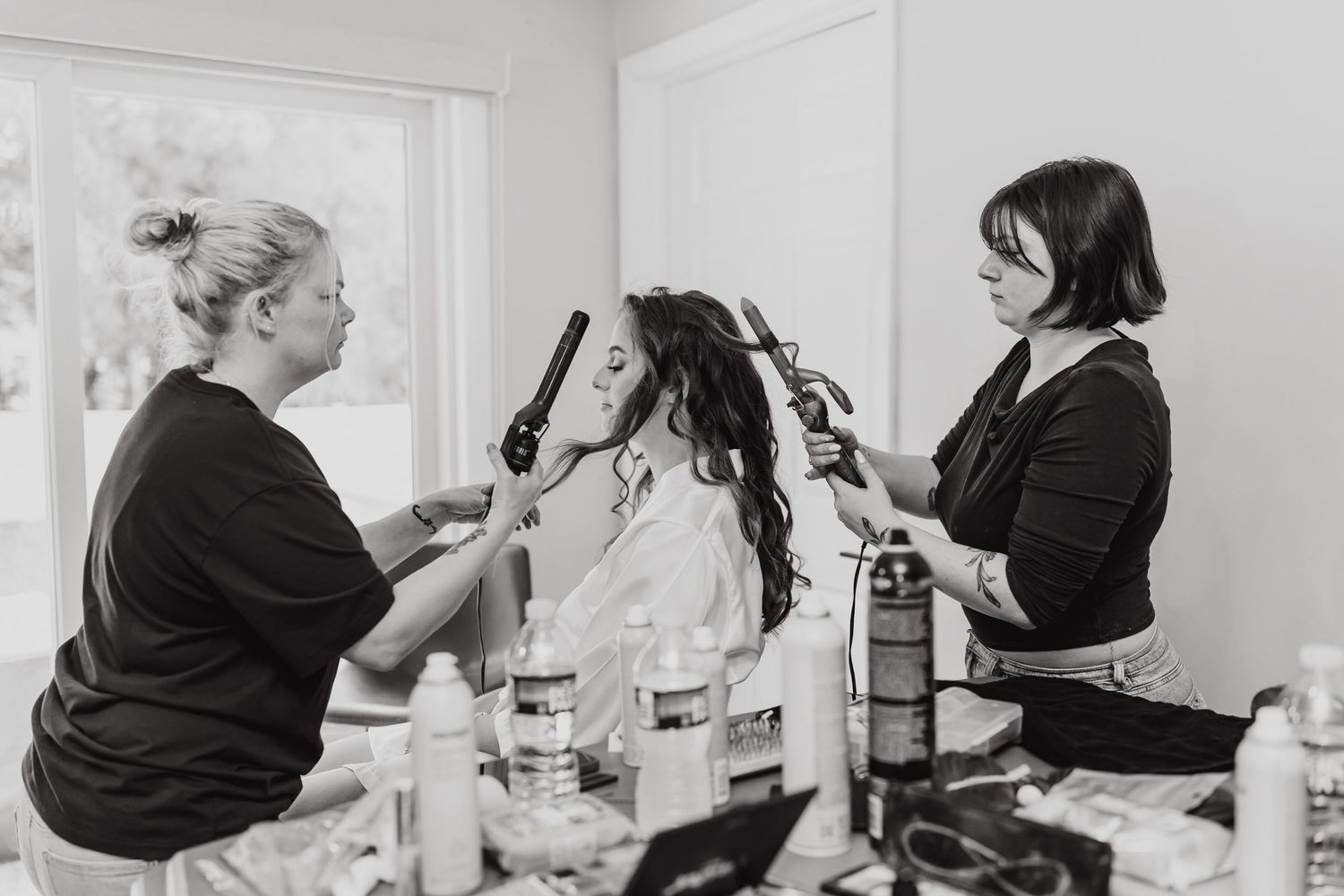 A series of black and white photos showing a hairstylist working on styling a client's hair in a salon setting.