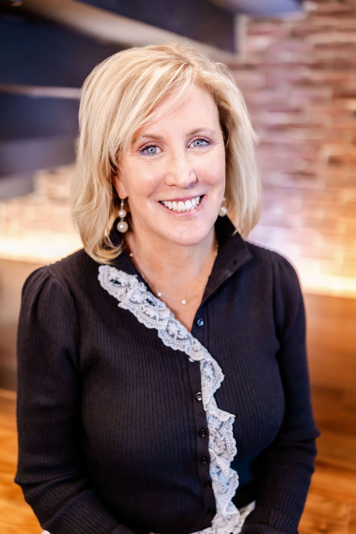 Professional headshots of someone wearing a black sweater with white lace accent in a warm studio setting.