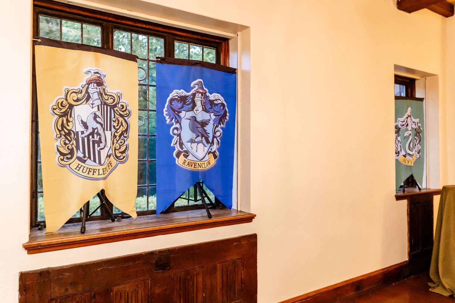 Hogwarts house banners displayed in window alcoves along a cream colored wall.