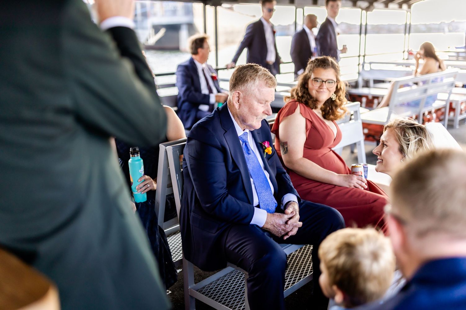 Wedding guests seated on boat deck with Baltimore waterfront views.