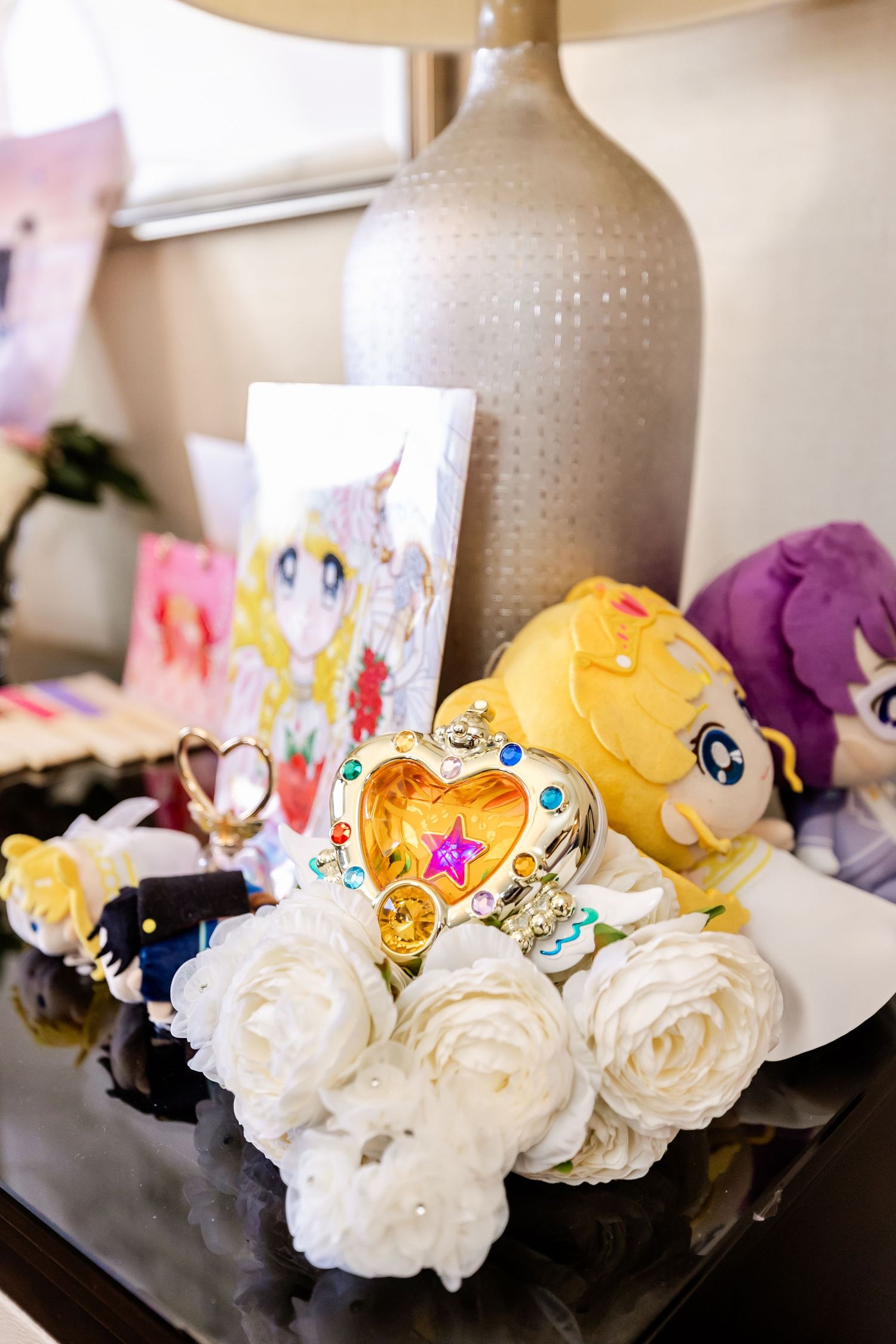 Decorative display featuring anime merchandise, plush toys and white roses around a ceramic vase.