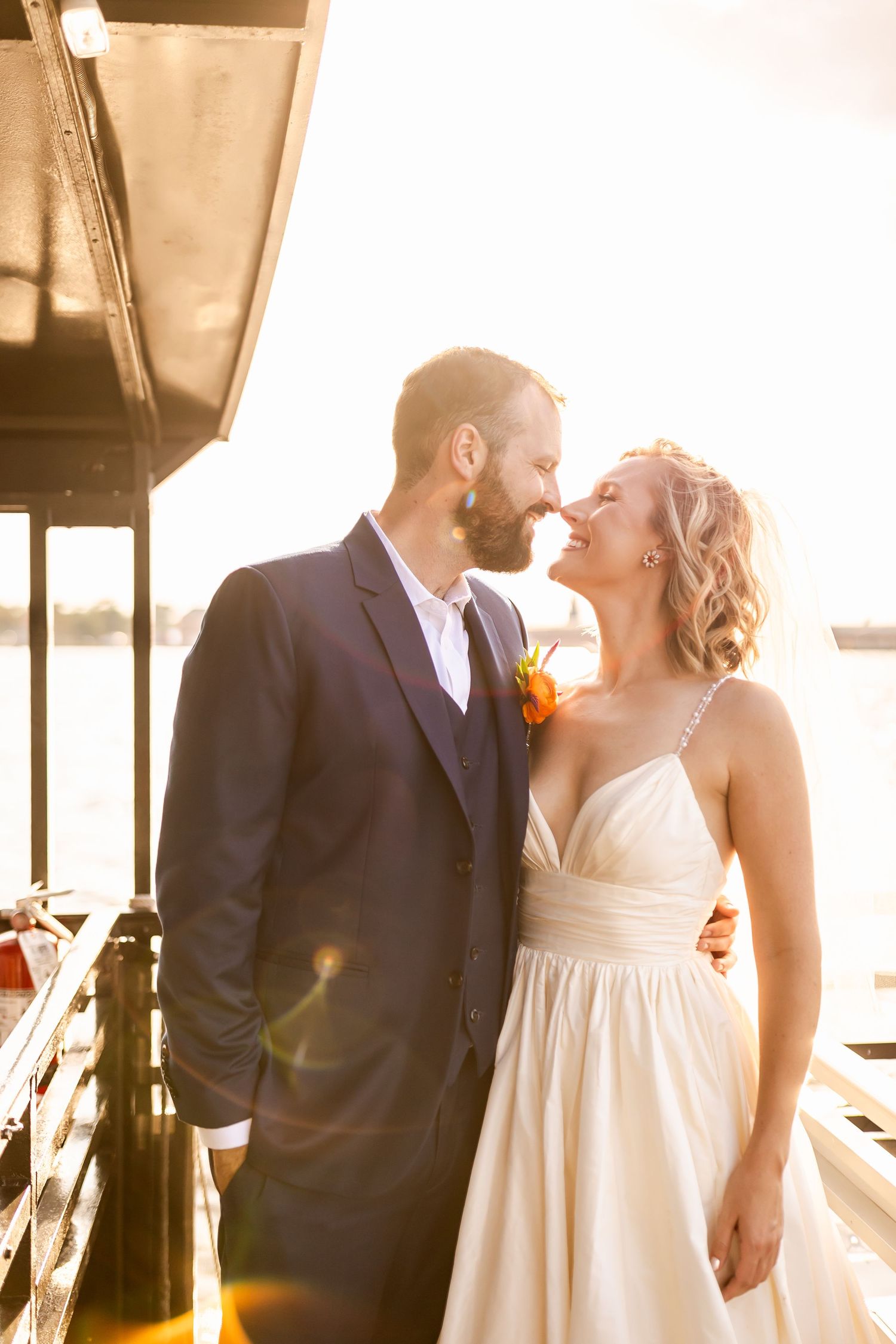 A romantic sunset moment between newlyweds on a waterfront deck.