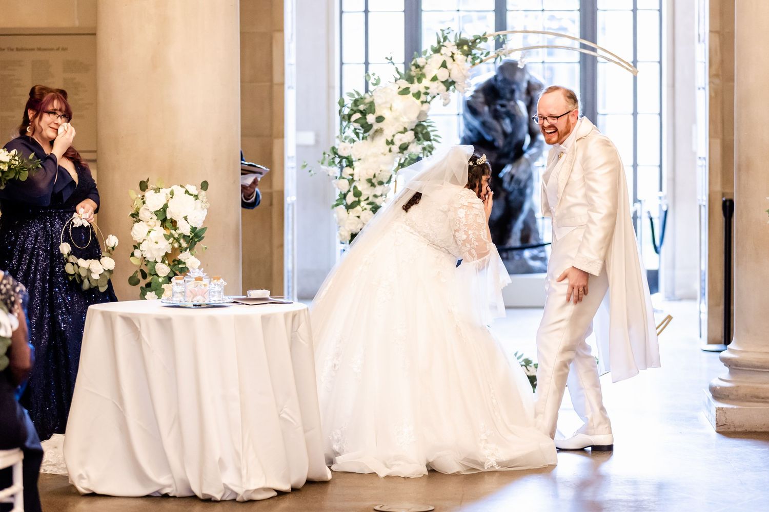 Couple signing documents during their wedding ceremony next to a white-draped table.
