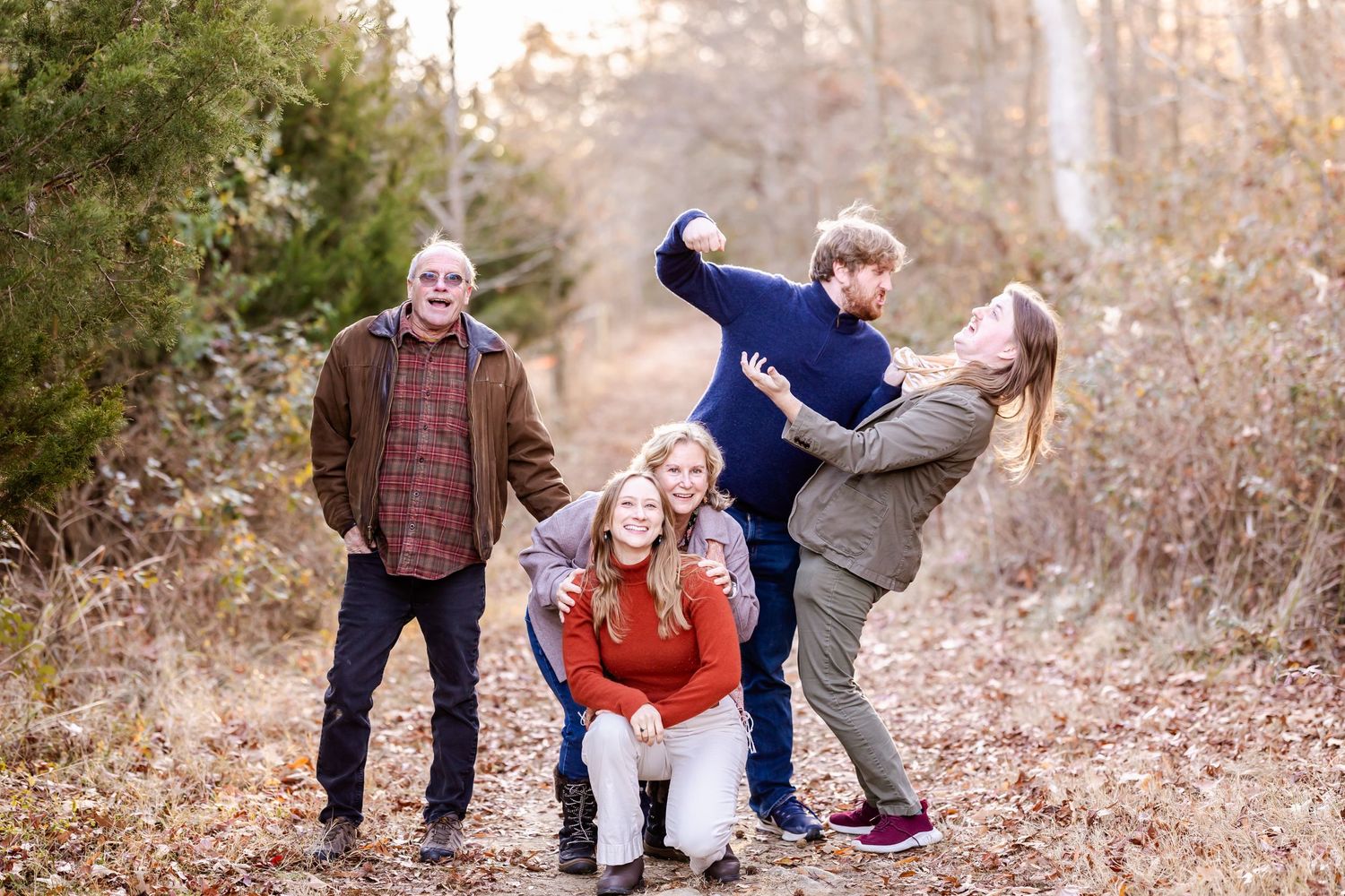 A playful group photo with people striking fun poses on a fall forest path.