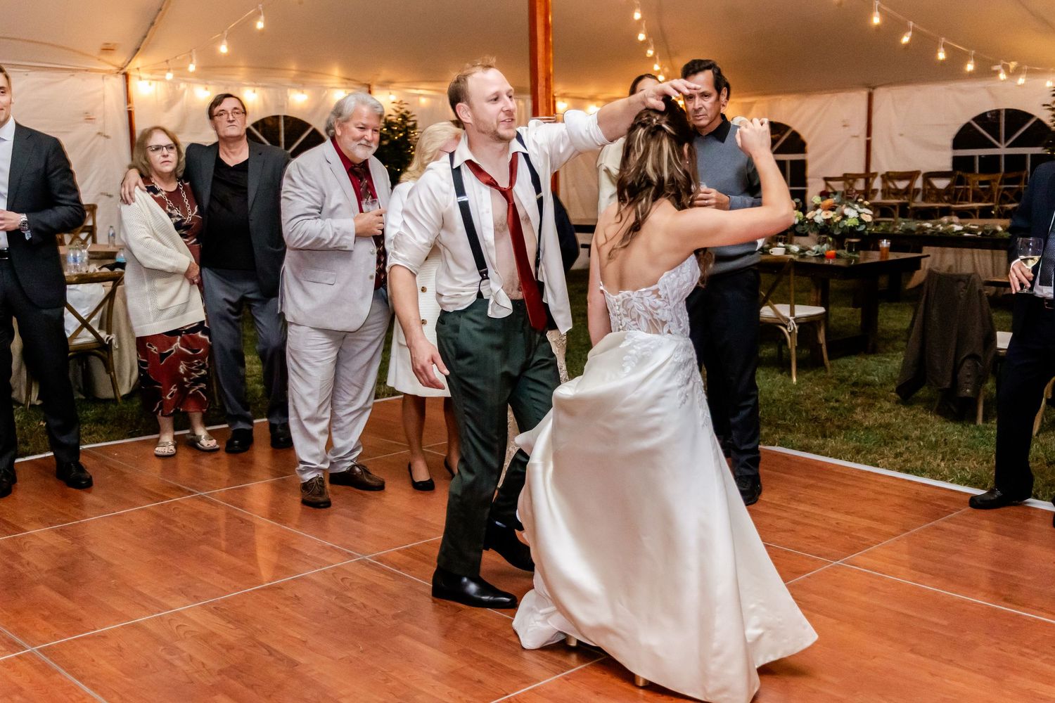 Couples dancing and celebrating on a wooden dance floor at an indoor wedding reception.