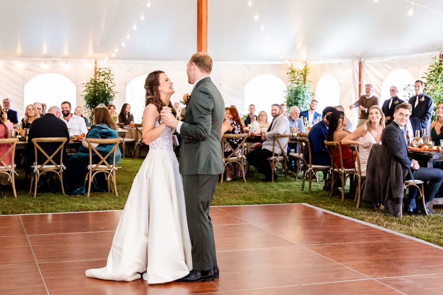 Wedding reception dance floor moments captured under elegant white tent with guests watching.