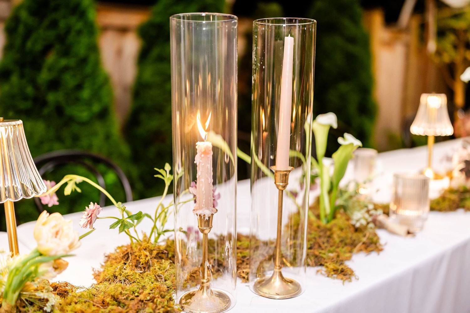 Elegant wedding table decorations with tall glass vases and natural greenery accents.