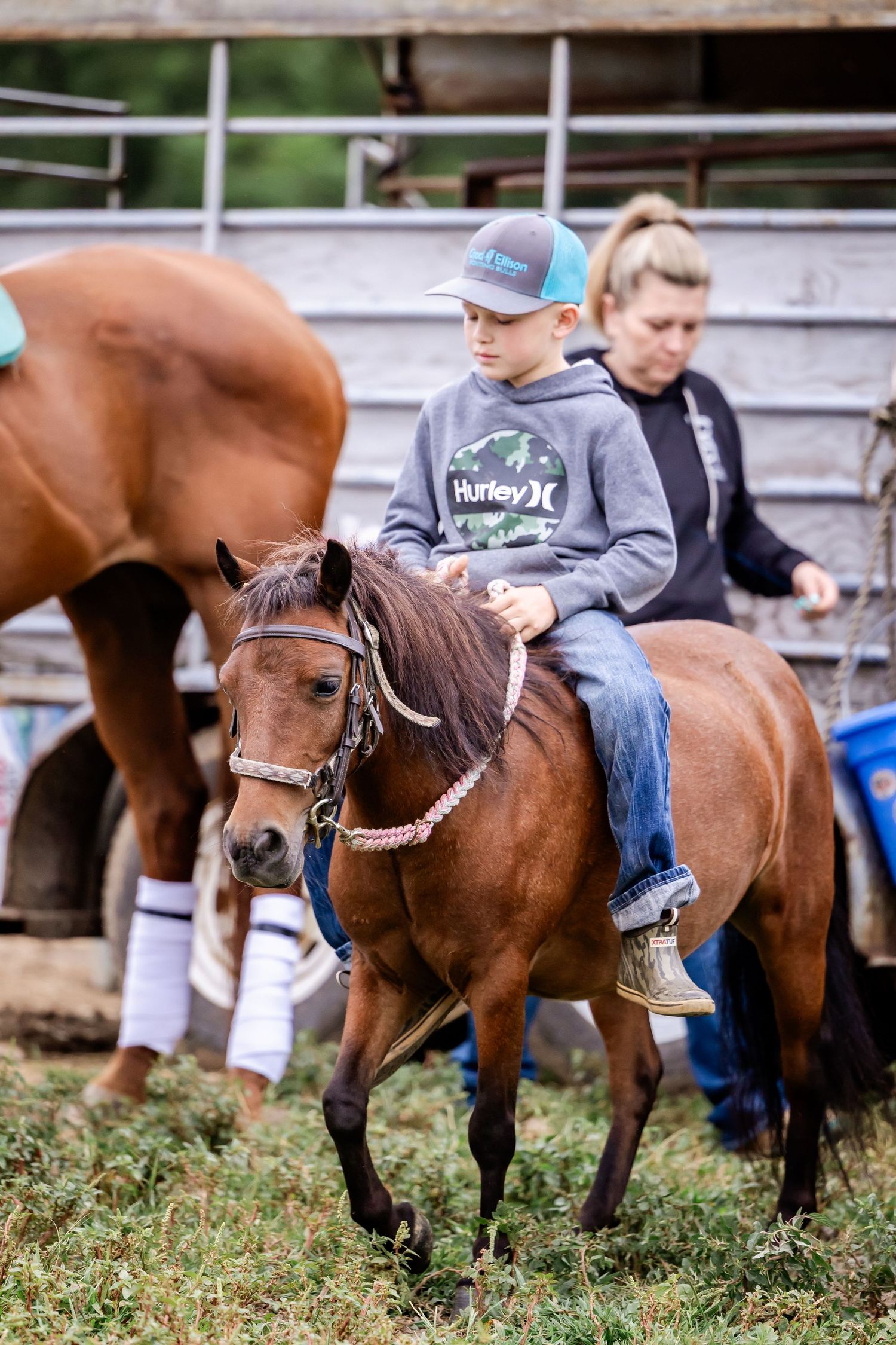 Row of horses and riders lined up near arena fence during equestrian event.