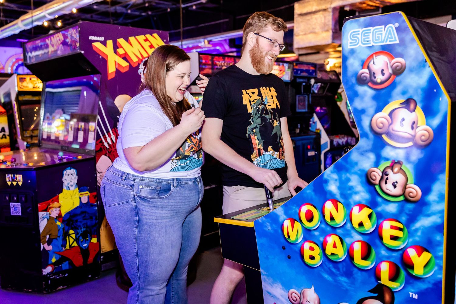 Players immersed in playing the Monkey Ball arcade game cabinet in a colorful gaming venue.