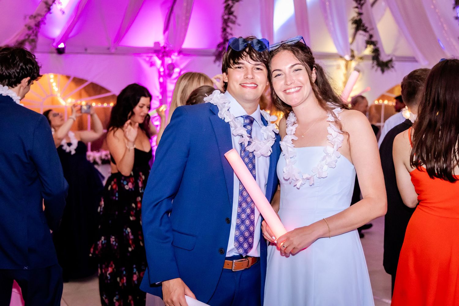 Wedding reception dance floor filled with guests under vibrant purple lighting.
