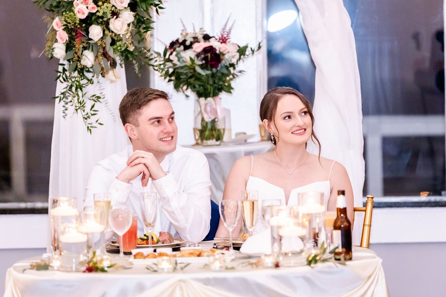 Wedding reception tables decorated with floral centerpieces and string lights.