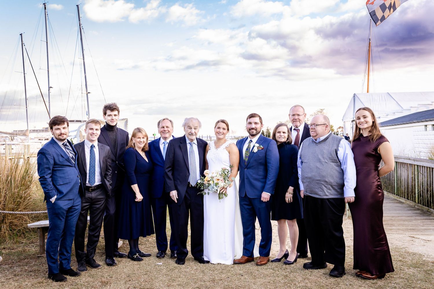 Bride and groom surrounded by family group photo at waterfront marina wedding.