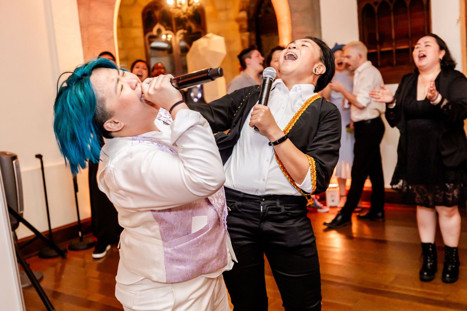 Two party guests enthusiastically singing karaoke together at a lively indoor celebration event.