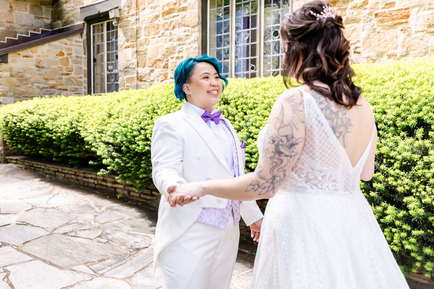 Wedding couple sharing an emotional first look moment outside a stone building.
