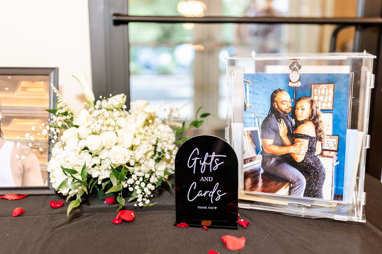 Wedding gift table with framed photo and floral decorations at reception.