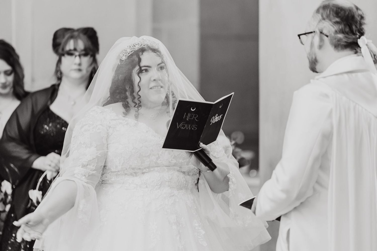 Black and white photo of a wedding ceremony with participants reading from prayer books.