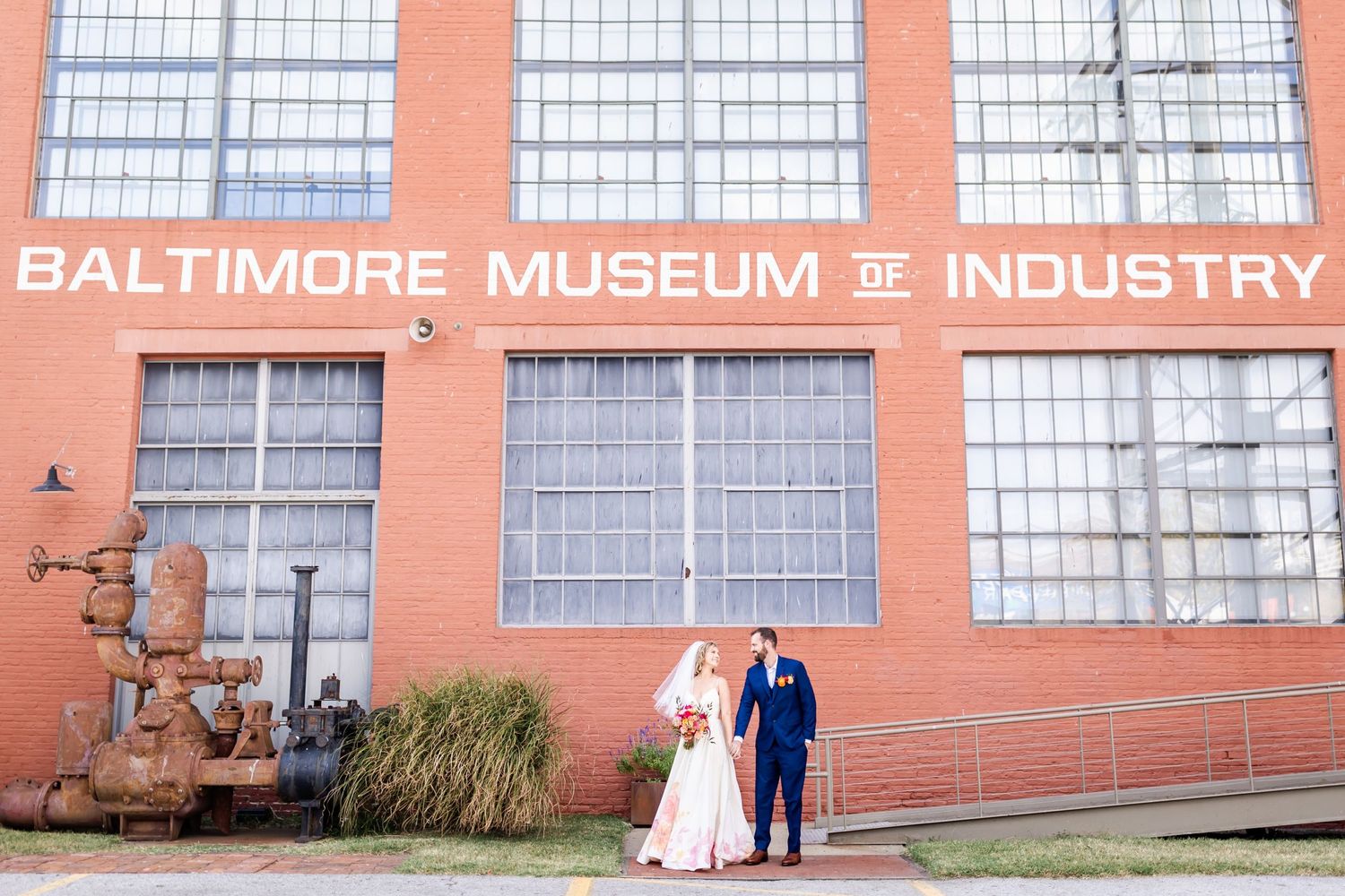 Wedding couple poses outside the Baltimore Museum of Industry brick building.