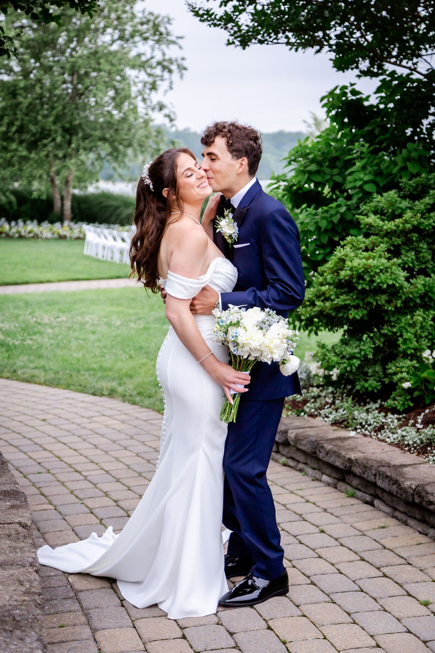 Romantic wedding couple sharing intimate moments on a stone patio surrounded by lush greenery.
