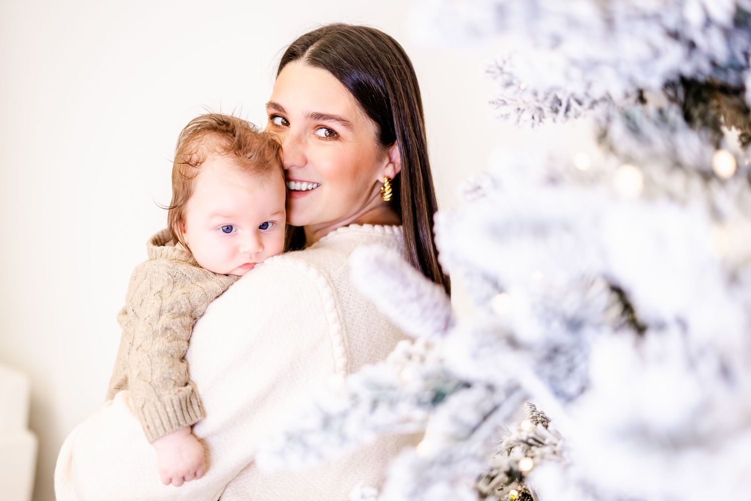 A winter portrait shows tender moment next to snowy frost-covered Christmas tree branches.