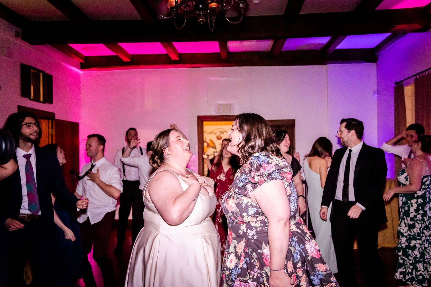 Wedding reception dance party with pink and purple lighting illuminating the crowd.