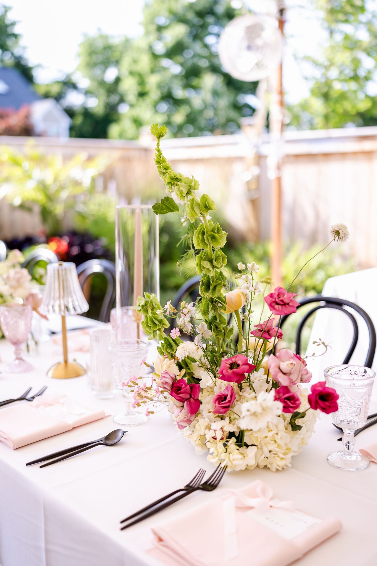 Elegant table settings with pink floral centerpieces and white linens at wedding reception.